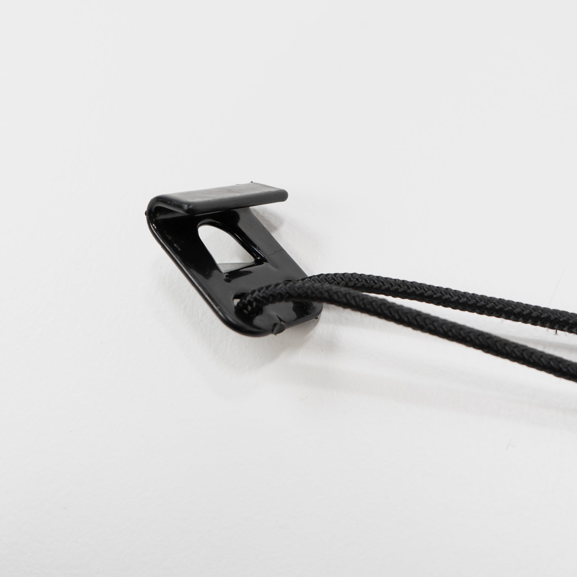 Schwarzer Klammerclip mit zwei schwarzen Schnüren auf weißem Hintergrund.