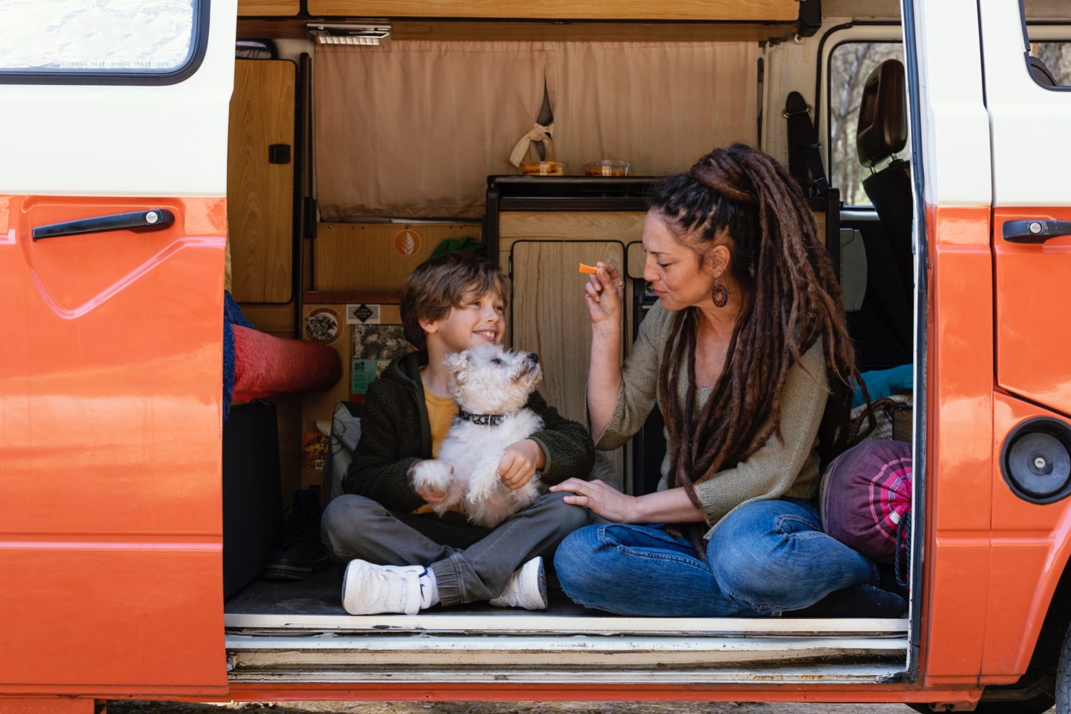 Mutter und Sohn spielen mit kleinem Hund im Van